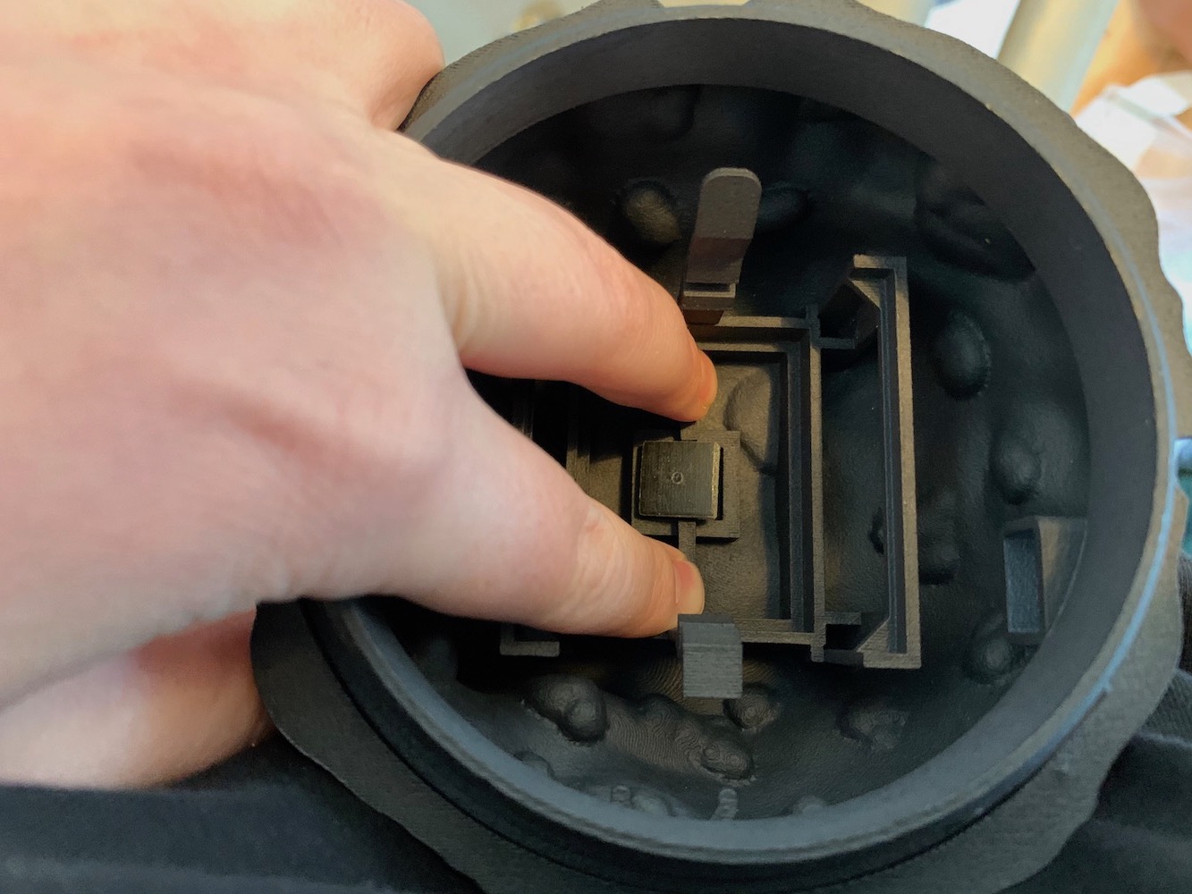 fingers holding back clips to push the rubber bung into the bottom of the Dustbox enclosure