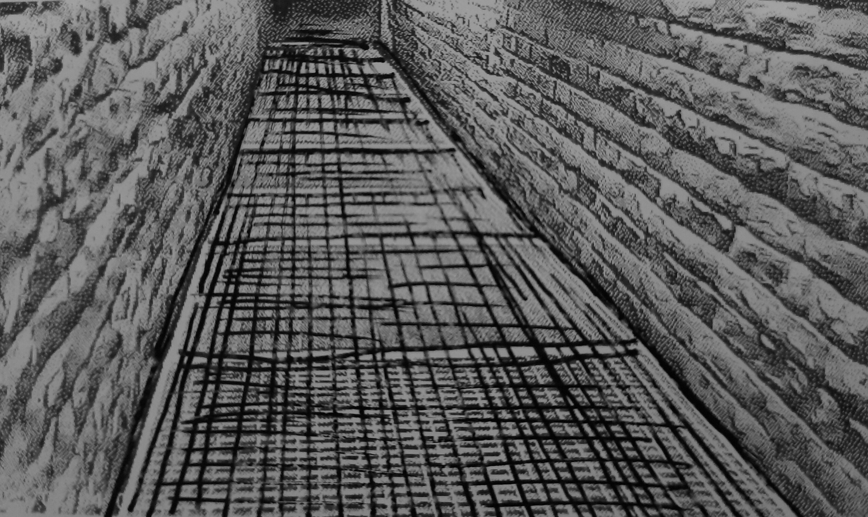 A narrow pathway with bricks on both sides, a metal grid on the floor