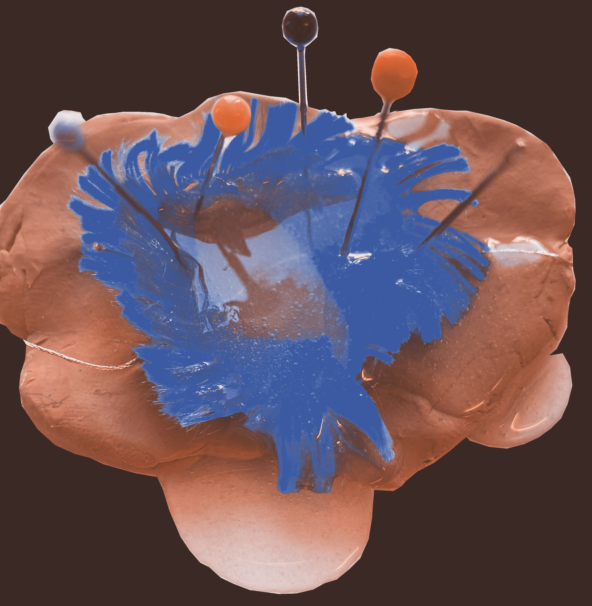 A clay shape is holding a fluffy blue textile thread. The thread is being held with pins, translucent silicone has been poured all over.